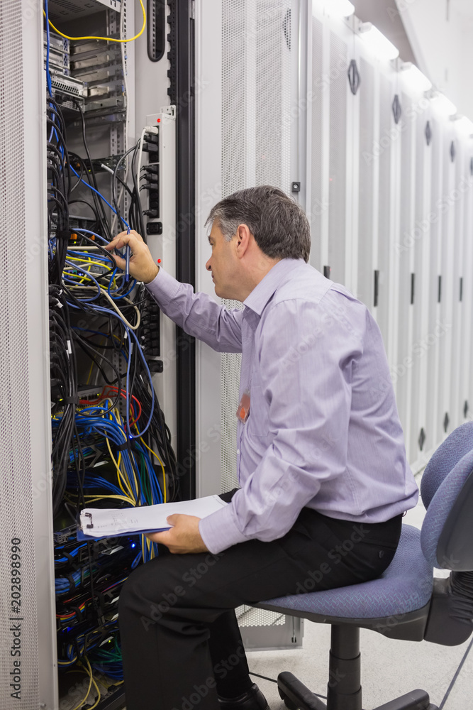 Poster technician with a clipboard checking servers