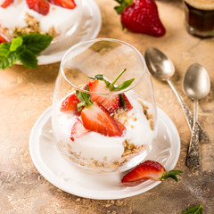 Dessert with strawberries and yoghurt on light brown background. Healthy breakfast food concept.