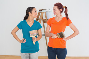 Friends with paint brushes and ladder in a new house