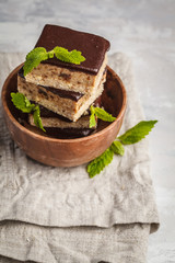 Raw vegan cake with chocolate, a stack of sliced pieces in wooden bowl, white background, copy space. 