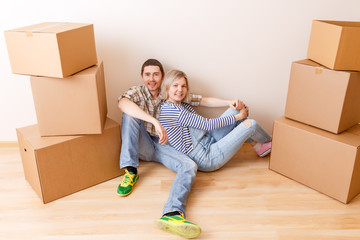 Fototapeta na wymiar Image of man and woman sitting on floor among cardboard boxes