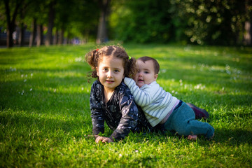 Naklejka na ściany i meble Two sisters playing in the grass in a park