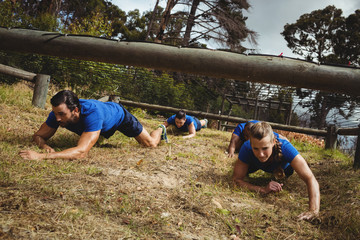 Fit people crawling under the net during obstacle course