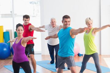 People doing warrior pose in yoga class