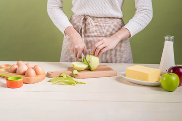 House wife wearing apron making. Steps of making cooking apple cake. Cutting green apple.