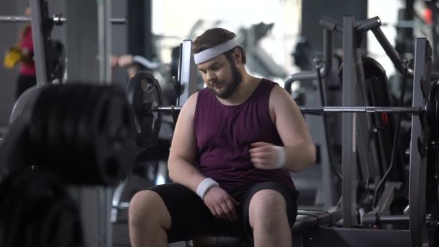 Tired fat man having rest after workout exercise, strength of muscles, training