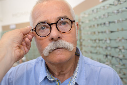 old man trying a pair of eyeglasses