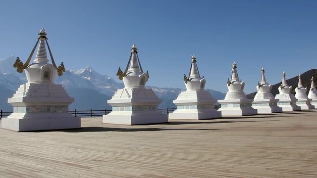 White Stupas at Feilai Temple in Deqing, Yunnan province, China. Meili snow mountains on the background from scenic view point on sunny day