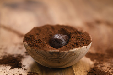 chocolate truffle in cacao powder in wood bowl on table