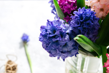 Bouquet of hyacinth flowers scissors rope over white stone background.