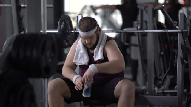Obese male drinking water after barbell exercise, restoring aqua balance, diet