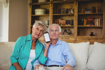 Senior couple using mobile phone in living room