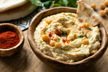 Homemade chickpea hummus in bowl served with pita bread and smoked paprika. Closeup view, selective focus