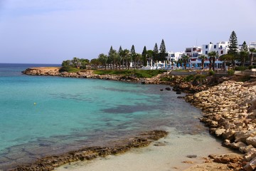Fototapeta na wymiar Blue beach umbrellas and sunbeds on Sandy Beach in Ayia Napa, Cyprus