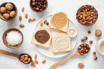 Fototapeta na wymiar Nut butter and bread toast on white plate. Assorted nut butter spread on white toast bread. Healthy eating, vegan, vegetarian, healthy lifestyle, nutrition concept