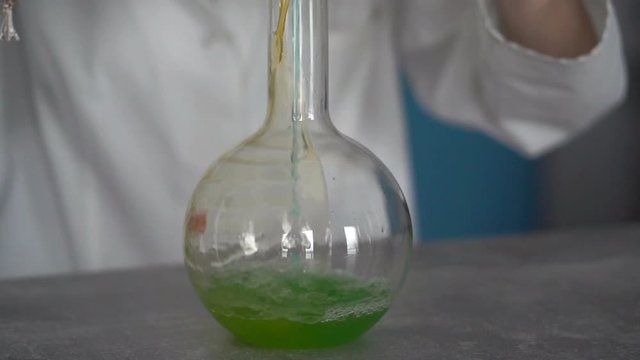 Woman scientist mixing chemicals in flask, slow motion
