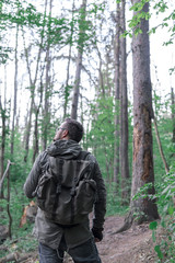 Young man with backpack walk at the green forest, active lifestyle hiking and travel concept, survive, vertical photo