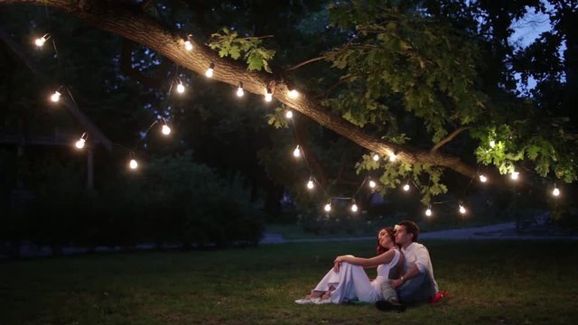 A couple is sitting in the park in the night lights. Photo in an old yellow style.