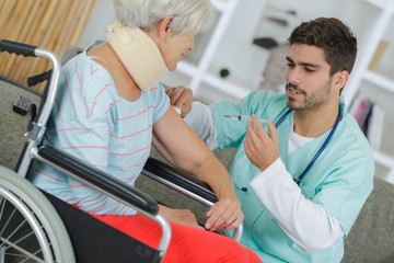Obraz premium nurse giving an injection to elderly woman at home
