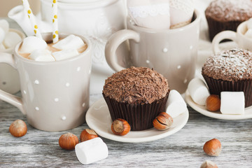 Cups with cacao and marshmallow, cupcakes and different decorations