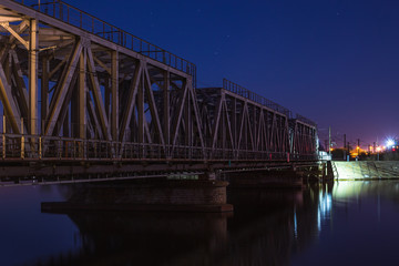 Railroad bridge over river at night, transportation construction