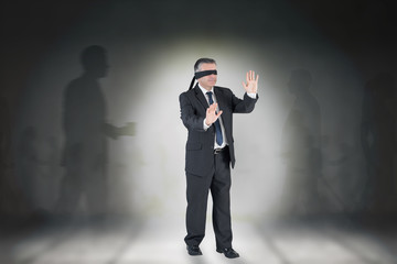 Composite image of mature businessman in a blindfold against grey room