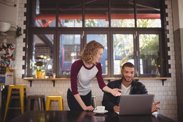 Young man and woman gesturing at laptop