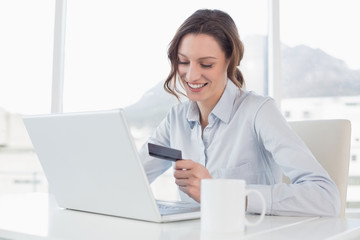 Smiling businesswoman doing online shopping in office