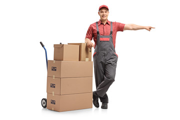 Mover leaning on a hand truck with a stack of boxes and pointing