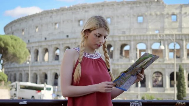 young tourist in Rome focused on the city map- colosseum in backround