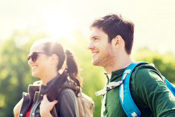 Fototapeta premium travel, hiking, backpacking, tourism and people concept - happy couple with backpacks walking outdoors