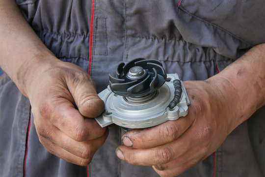 Mechanic holding water pump for car with sealing paste added