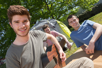 guy playing guitar at campsite in nature