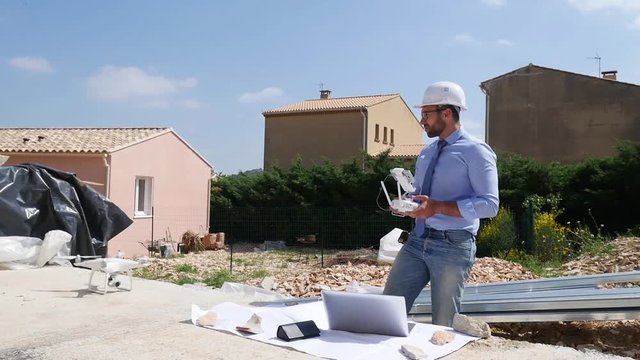 handsome architect flying inspection drone for aerial view of a house construction site industry slow motion 50fps