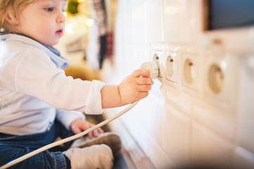 Toddler boy in dangerous situation at home. Child safety concept.