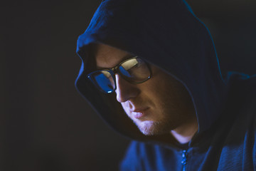 cybercrime, hacking and people concept - close up of hacker in glasses and hoodie