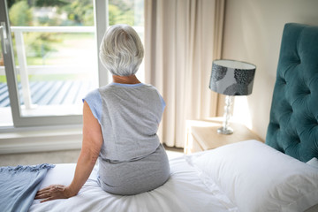 Senior woman sitting on bed in bedroom
