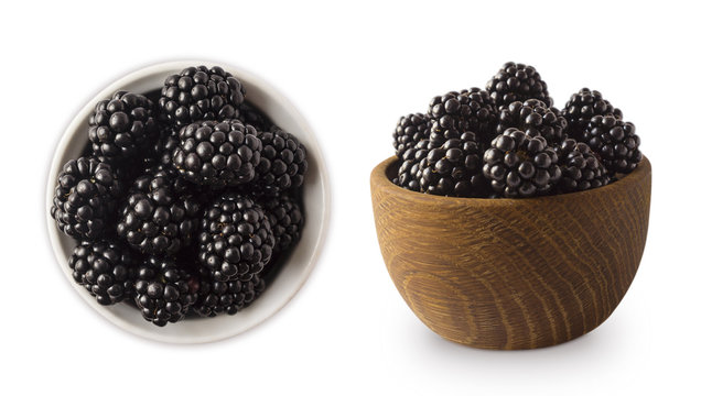 Blackberries in a wooden bowl with copy space for text. Ripe and tasty black berry isolated on white background.
