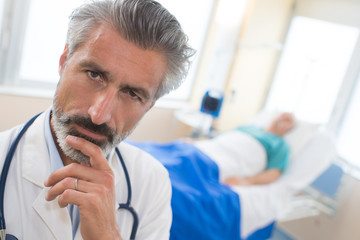 thoughtful doctor sitting at meeting in hospital
