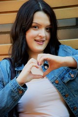 smiling young girl is making heart with fingers