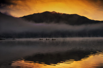 Obraz na płótnie Canvas Silhouette fisherman at Shoji lake during sunrise