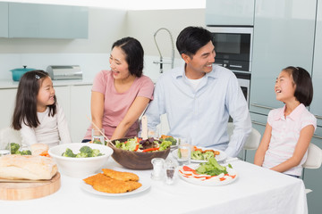 Obraz na płótnie Canvas Cheerful family of four enjoying healthy meal in kitchen