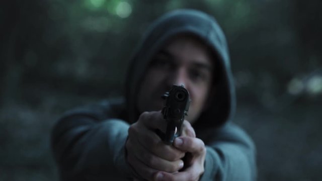 violent hodeed man pointing gun to the camera-outdoor