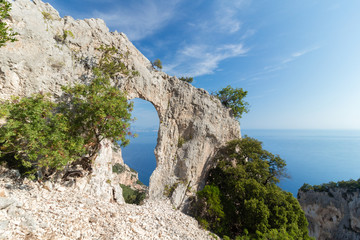 Fototapeta na wymiar Italy, Sardinia, Baunei - Natural arch in wild sardinian nature