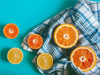 Citrus fruit Flat lay Halves of orange, lemon and mandarin lying on a checkered blue and white tablecloth on a bright blue background Photo template in top view with copy space