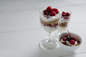 Three cups of yogurt with raspberries and pomegranate seeds