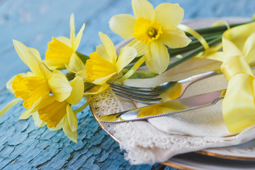 Fototapeta na wymiar Set of tableware and a bouquet of yellow narcissus