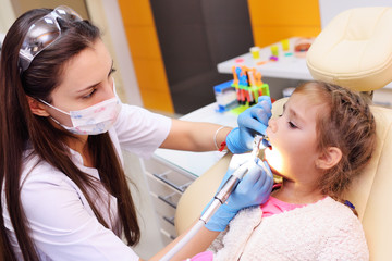 The dentist examines a child's teeth in a dental chair.