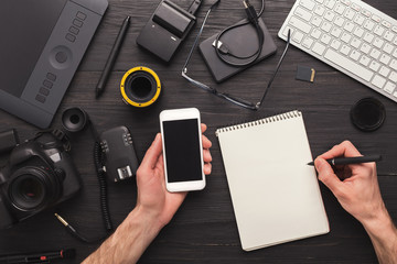 Photographer taking notes while using smartphone