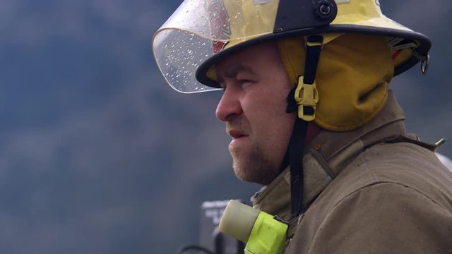 Profile of a firefighter talking to a co-worker at a fire scene